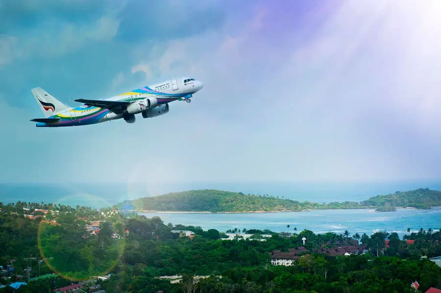 Passenger aircraft departing over a tropical island coastline